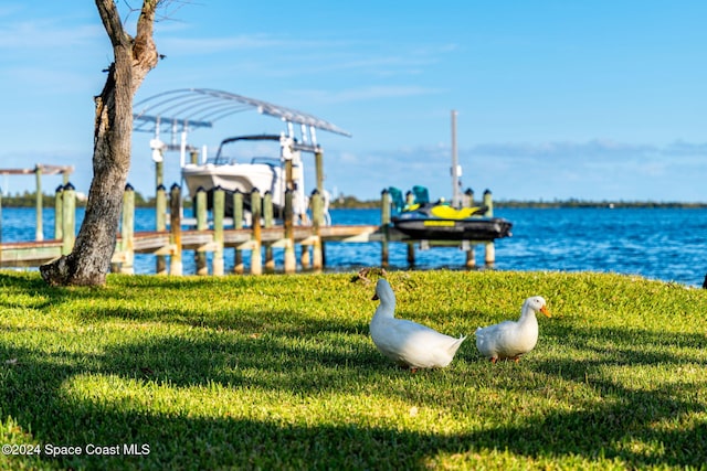 view of dock with a water view and a lawn