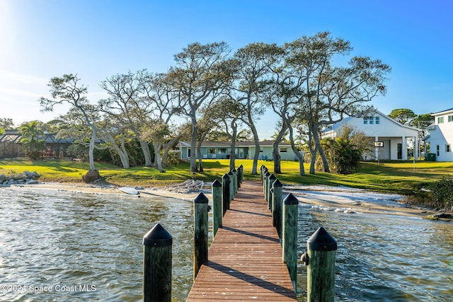 view of dock featuring a lawn and a water view