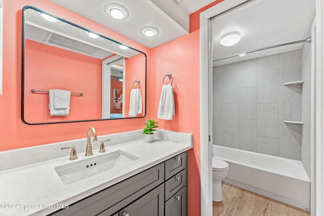 full bathroom featuring hardwood / wood-style floors, tiled shower / bath combo, toilet, and vanity