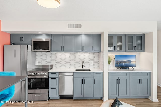 kitchen featuring light hardwood / wood-style floors, sink, stainless steel appliances, and tasteful backsplash