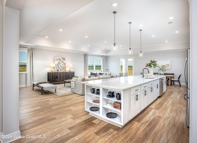 kitchen featuring sink, decorative light fixtures, a center island with sink, light hardwood / wood-style flooring, and white cabinets