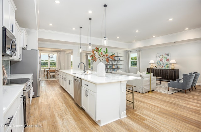 kitchen with a wealth of natural light, a kitchen island with sink, white cabinets, and stainless steel appliances