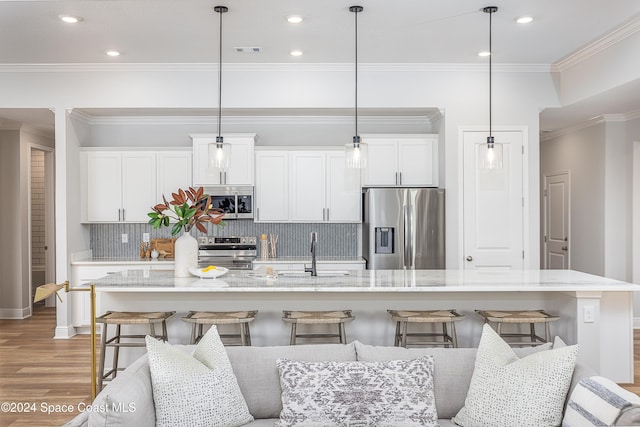 kitchen with decorative light fixtures, sink, stainless steel appliances, and a center island with sink