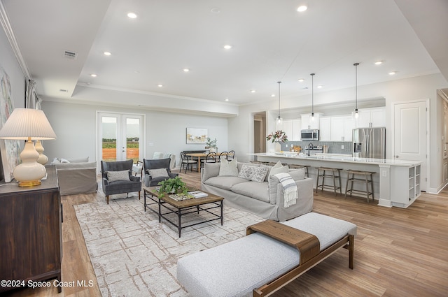 living room with light hardwood / wood-style floors, crown molding, and french doors