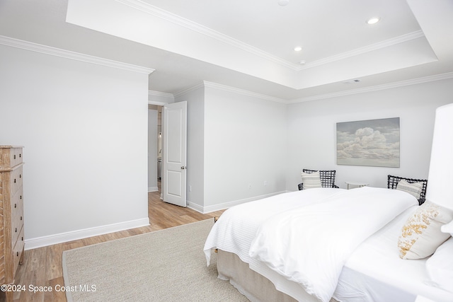 bedroom featuring a raised ceiling, crown molding, and light wood-type flooring