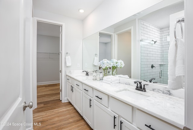 bathroom featuring hardwood / wood-style floors, vanity, and a tile shower