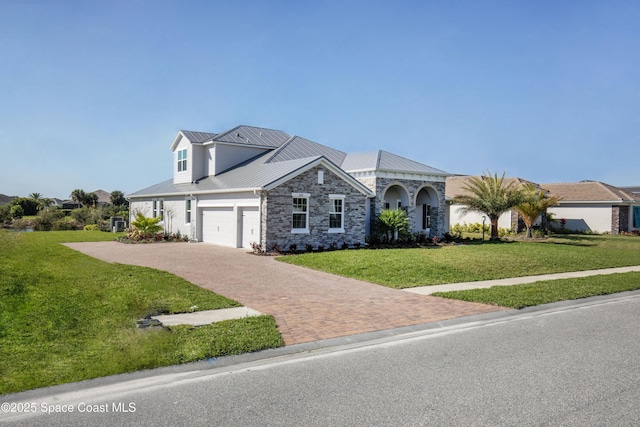 view of front of property featuring a front yard, a garage, stone siding, decorative driveway, and metal roof