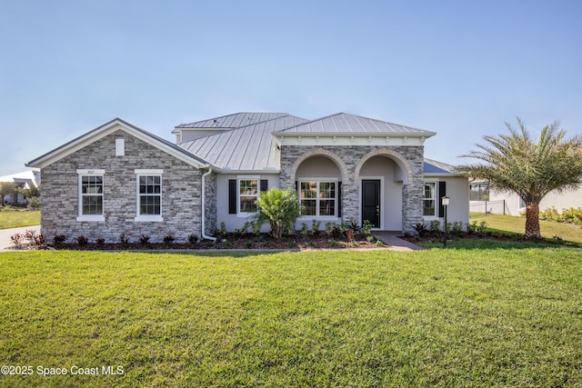 view of front facade with a standing seam roof, a front yard, stucco siding, and metal roof