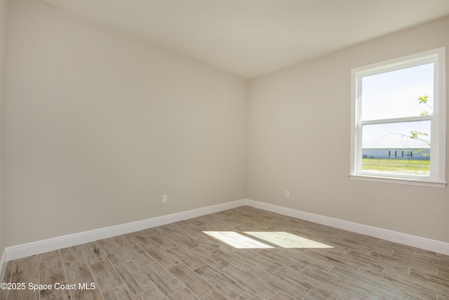 spare room featuring light wood-type flooring and baseboards