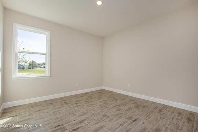 spare room featuring baseboards and light wood finished floors