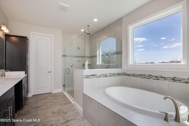 bathroom with visible vents, a shower stall, wood finish floors, a bath, and vanity