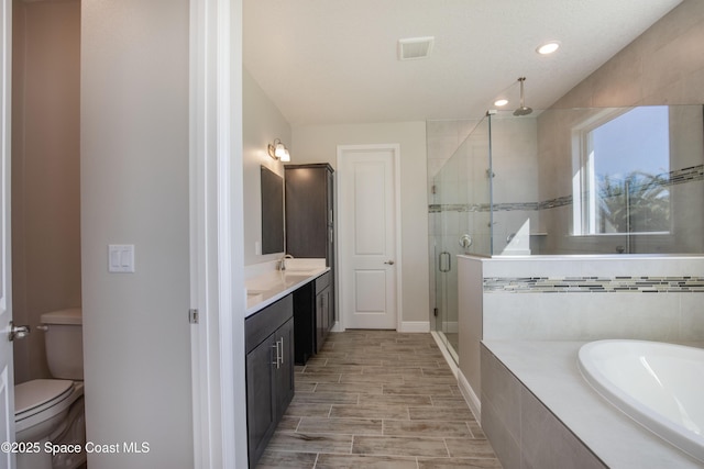 bathroom with vanity, a bath, visible vents, a stall shower, and toilet