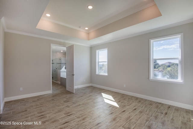 unfurnished bedroom with a raised ceiling, baseboards, light wood-type flooring, and ornamental molding