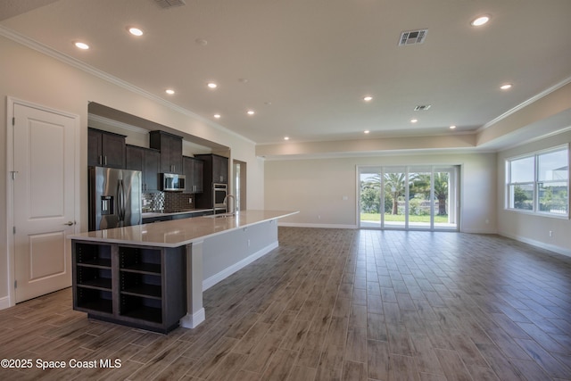 kitchen featuring visible vents, open floor plan, a center island with sink, appliances with stainless steel finishes, and wood finished floors