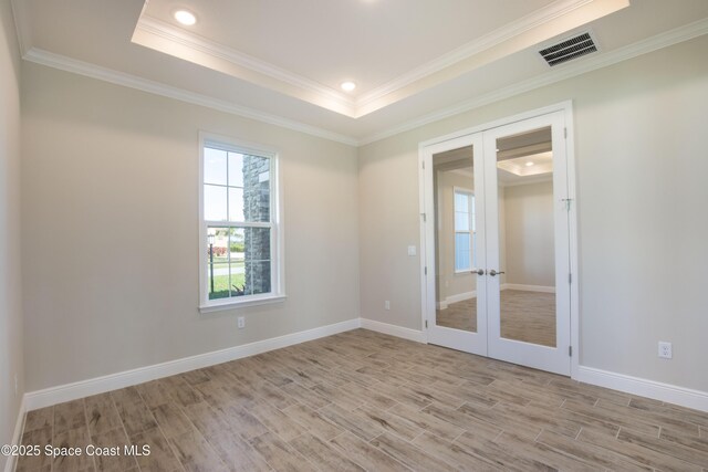 unfurnished room featuring a tray ceiling, french doors, visible vents, and light wood finished floors