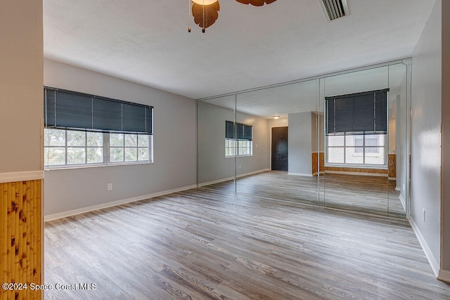 unfurnished room featuring plenty of natural light, ceiling fan, and light wood-type flooring