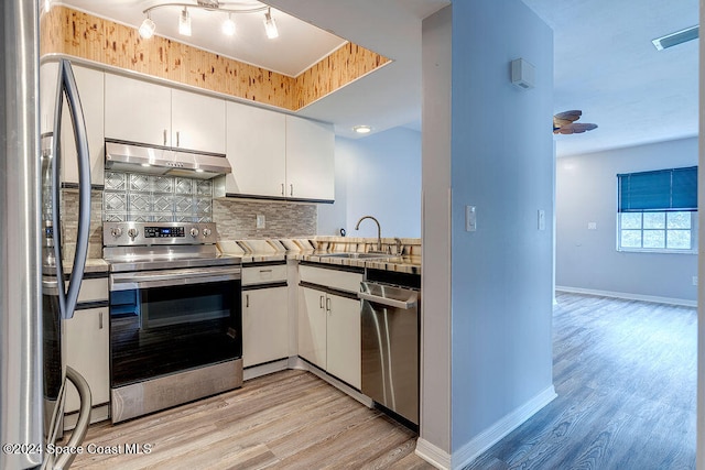 kitchen with sink, white cabinets, stainless steel appliances, and light hardwood / wood-style flooring