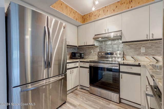 kitchen with light wood-type flooring, stainless steel appliances, white cabinetry, and tasteful backsplash