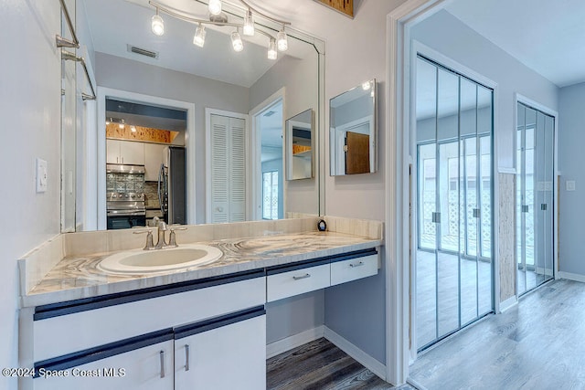 bathroom featuring decorative backsplash, wood-type flooring, and vanity