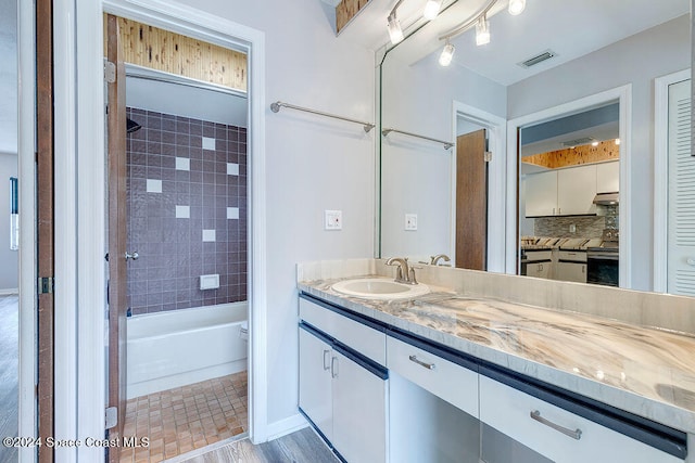 bathroom with decorative backsplash, vanity, wood-type flooring, and tiled shower / bath combo