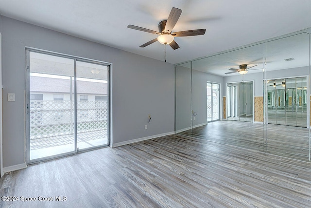 empty room featuring a wealth of natural light, ceiling fan, and light hardwood / wood-style floors