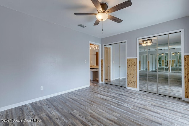 unfurnished bedroom featuring two closets, ceiling fan, light hardwood / wood-style floors, and ensuite bathroom