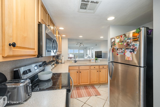 kitchen with appliances with stainless steel finishes, light brown cabinetry, a textured ceiling, sink, and light tile patterned flooring