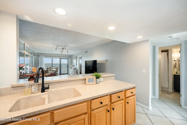 kitchen with light tile patterned floors, light brown cabinets, a textured ceiling, and sink