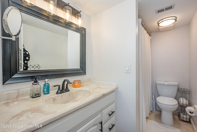 bathroom with toilet, vanity, and tile patterned floors