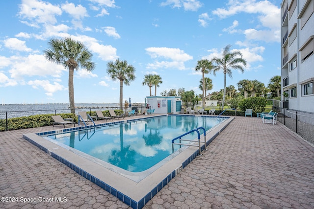 view of swimming pool with a patio and a water view