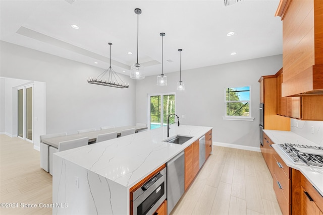 kitchen with sink, light stone counters, premium range hood, pendant lighting, and a spacious island