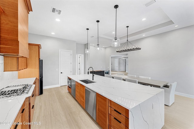 kitchen featuring a large island, sink, light stone counters, pendant lighting, and appliances with stainless steel finishes