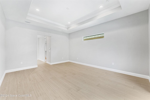 unfurnished room with light wood-type flooring and a tray ceiling