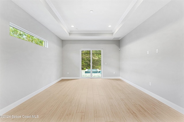 unfurnished room with crown molding, light hardwood / wood-style flooring, and a tray ceiling