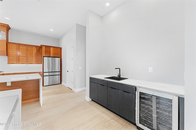 kitchen with wine cooler, stainless steel fridge, sink, and light hardwood / wood-style flooring