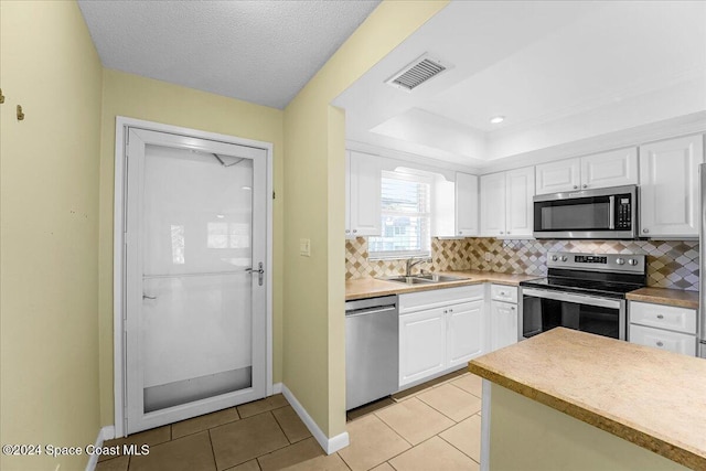 kitchen featuring white cabinetry, sink, light tile patterned floors, and appliances with stainless steel finishes