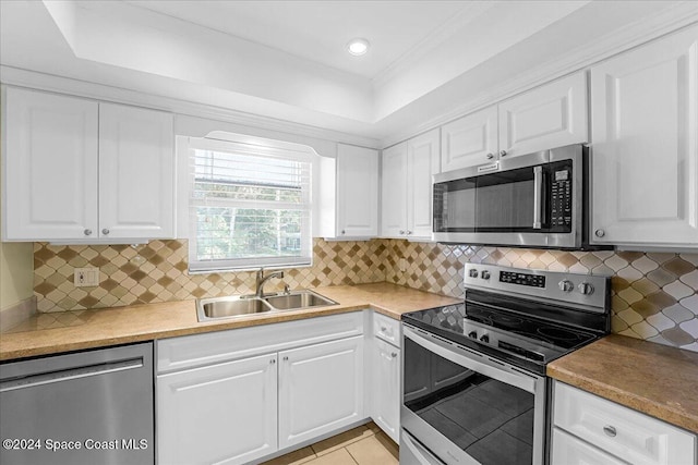 kitchen with tasteful backsplash, sink, white cabinets, and stainless steel appliances