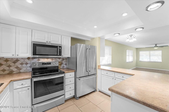 kitchen featuring white cabinetry, backsplash, appliances with stainless steel finishes, and a tray ceiling