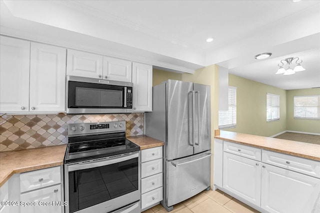 kitchen featuring white cabinets, decorative backsplash, light tile patterned floors, and stainless steel appliances