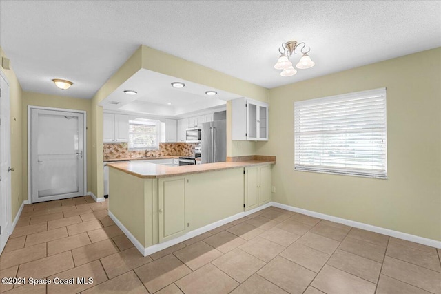 kitchen featuring plenty of natural light, white cabinetry, kitchen peninsula, and appliances with stainless steel finishes