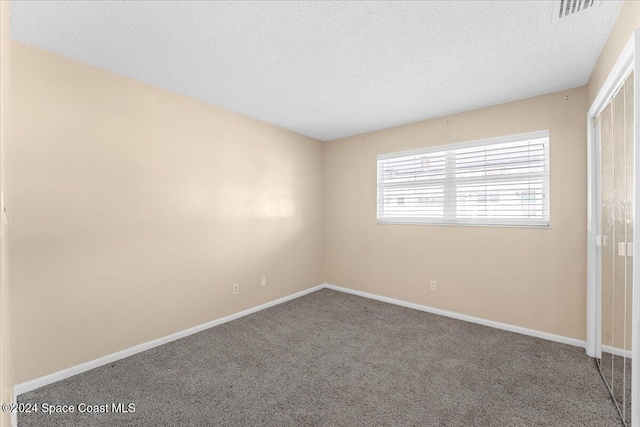 spare room featuring carpet flooring and a textured ceiling