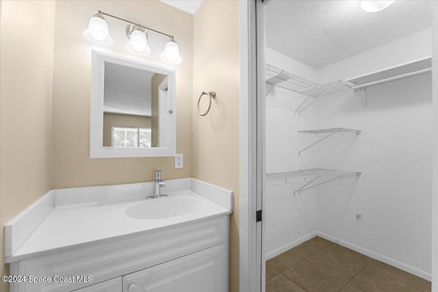 bathroom featuring tile patterned flooring, vanity, and a textured ceiling