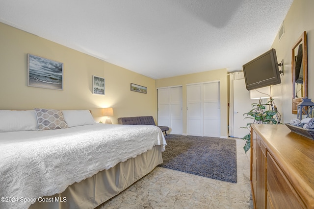 bedroom featuring a textured ceiling and two closets