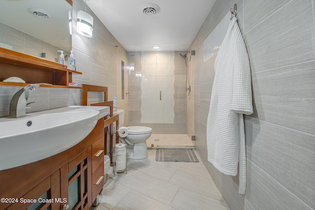 bathroom featuring tile patterned floors, an enclosed shower, vanity, tile walls, and toilet