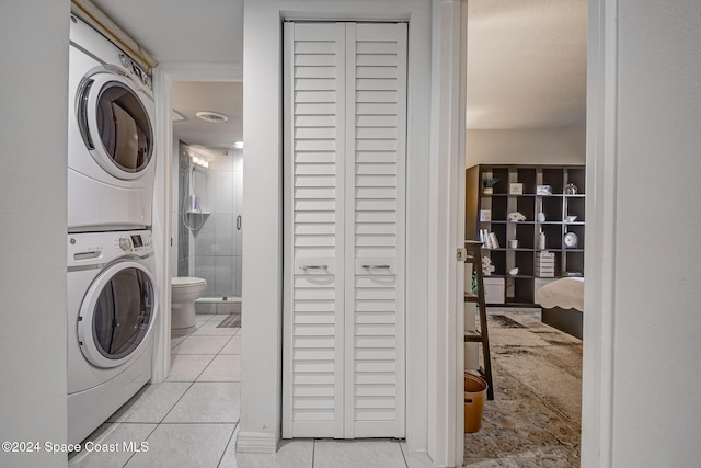 washroom featuring stacked washer and clothes dryer and light tile patterned flooring