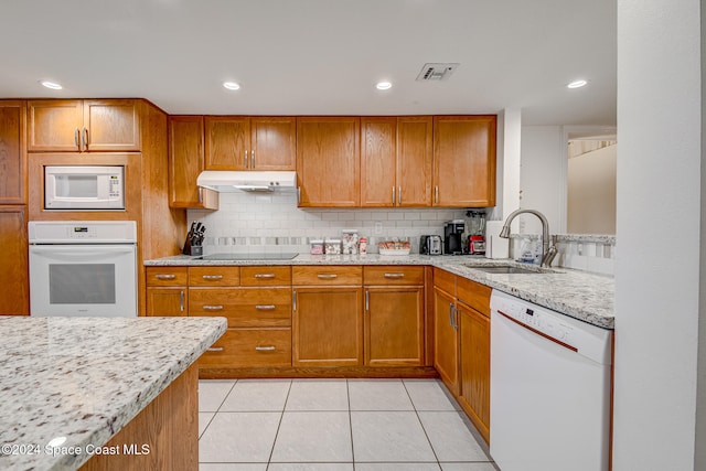 kitchen featuring light stone countertops, sink, light tile patterned flooring, and white appliances