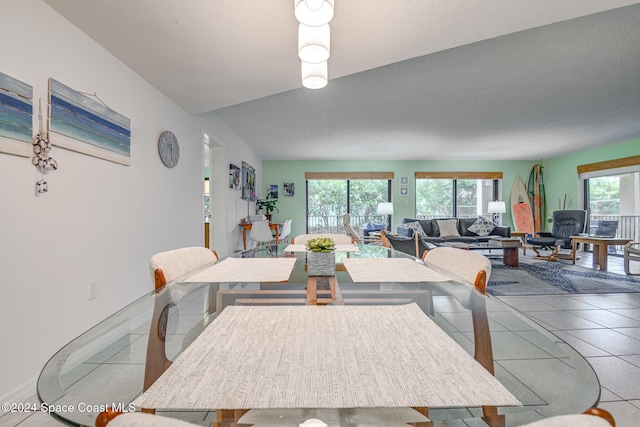 dining area featuring tile patterned floors, plenty of natural light, and lofted ceiling