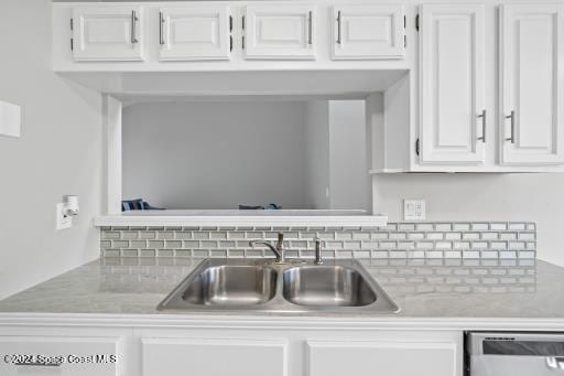 kitchen with dishwashing machine, sink, and white cabinets