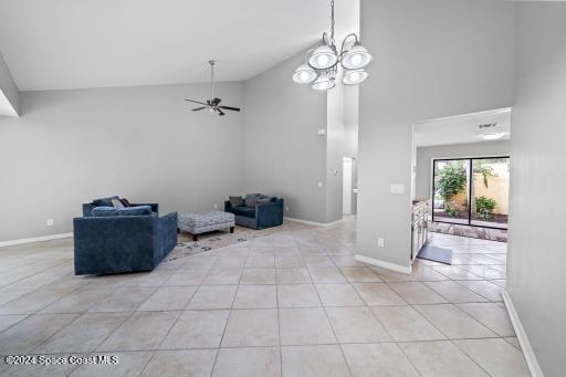 interior space with light tile patterned floors, ceiling fan with notable chandelier, and high vaulted ceiling