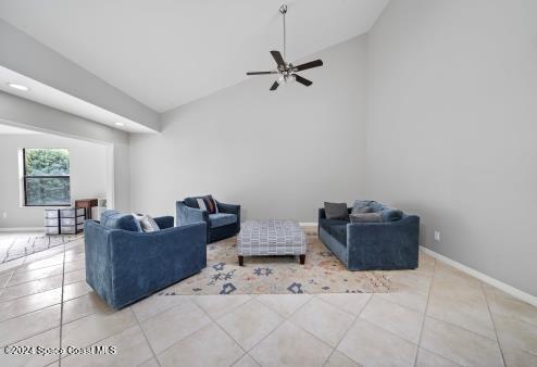 tiled living room with ceiling fan and high vaulted ceiling